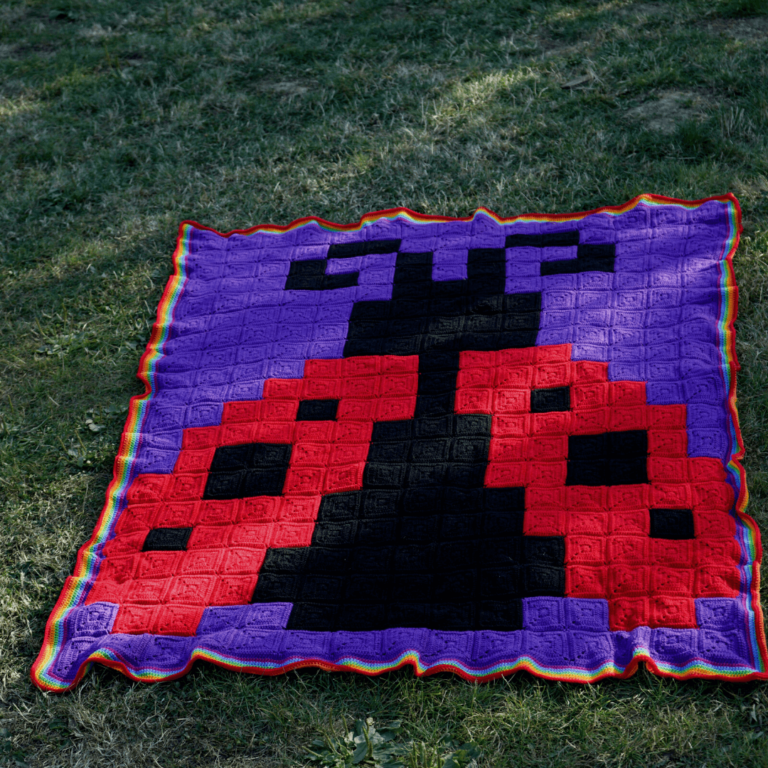 Crocheted Space Invader blanket grass
