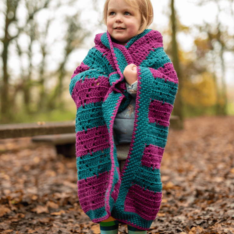 Toddler in crochet blanket outdoors