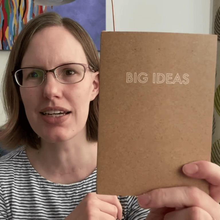 Woman holding 'BIG IDEAS' notebook